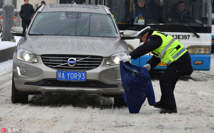 风雪中的感动 武汉交警脱下上衣放冰面上推车