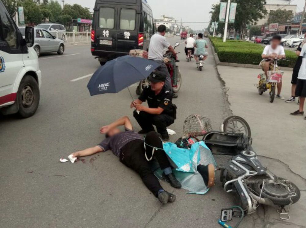 男子受伤倒地 曲阜特警为其撑伞等待120救援