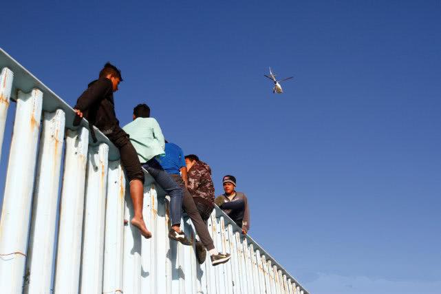 “特朗普，我们来了！”第一批“大篷车移民”抵达美墨边境，骑上边境墙