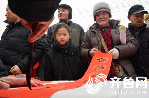 1月30日，在滨城区“三下乡”活动现场，书法爱好者在给群众写春联