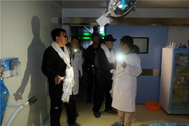 因当地经常停电，烟台毓璜顶医院援藏代表团一行打着手电现场了解当地医院手术室情况
