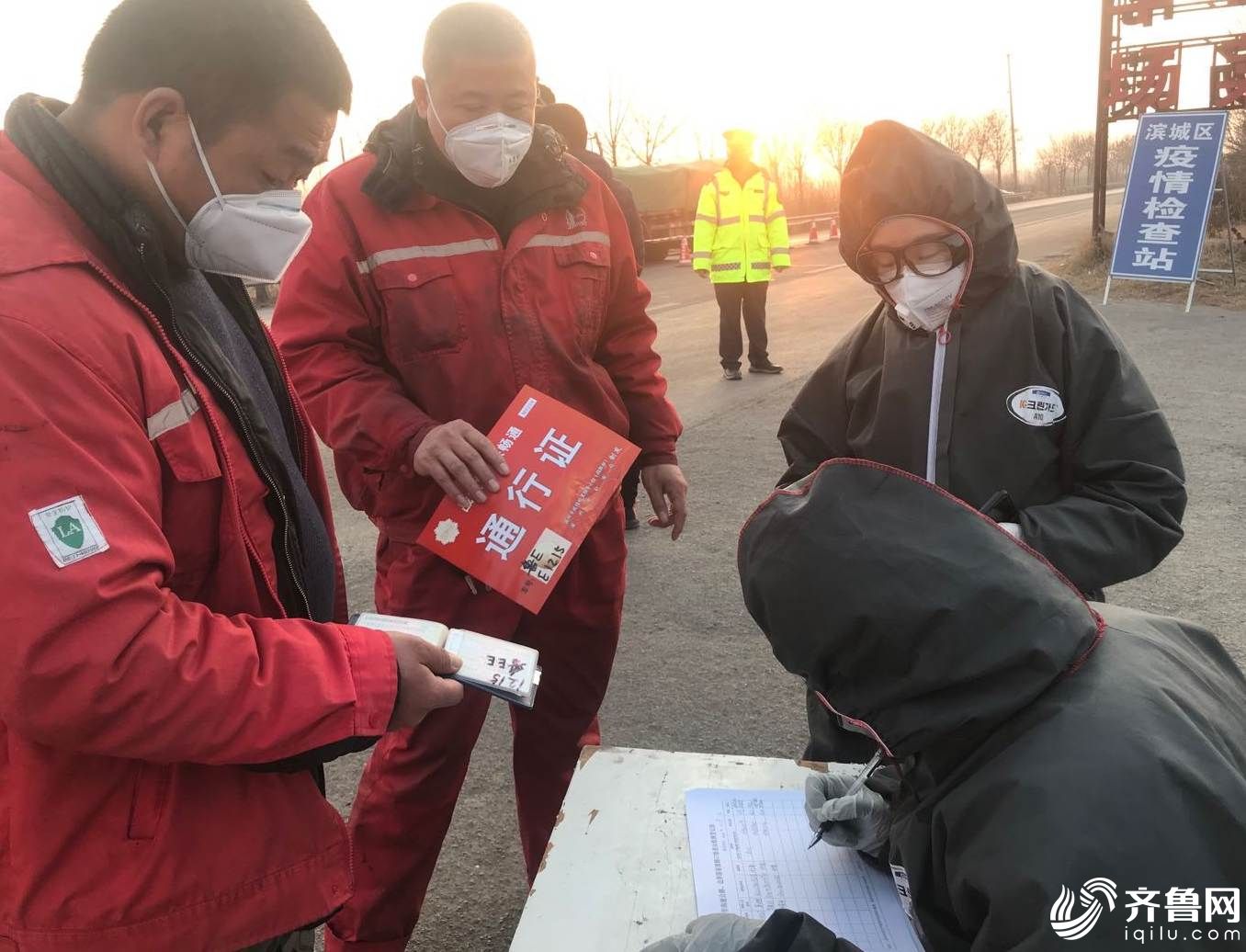 在国道220滨州-东营界疫情监测点，值守人员给过往人员测量体温并登记信息