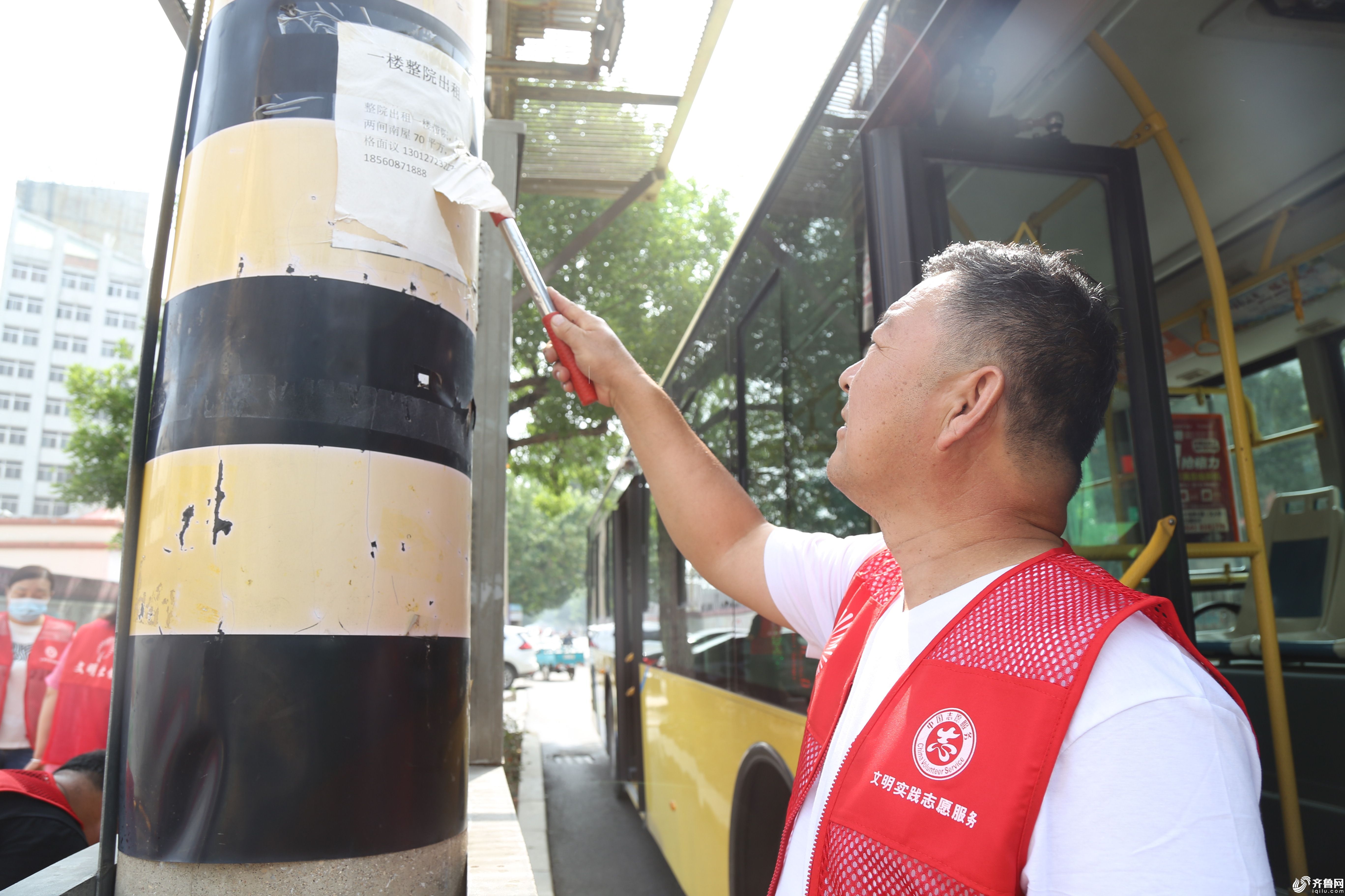 7月4日，滨城区北镇街道志愿者在黄河三路渤海四路对灯杆上的小广告进行清理。