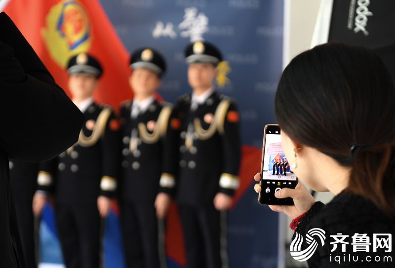 2022年1月7日，山东省东营市，一名警嫂用手机为自己的丈夫与战友拍照纪念。