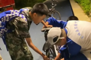 男孩自行车出故障 高年级同学热心帮忙