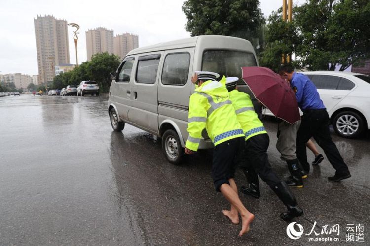 市民抓拍！云南昭通“赤腳交警”冒雨幫市民推車