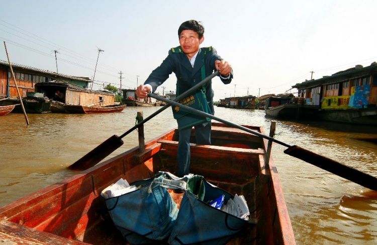 2013年，水上郵路投遞員唐真亞劃著小木船在湖區投遞。劉春平攝